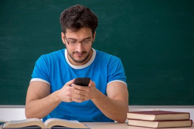 Sınıfta akıllı telefon tutan genç bir öğrenci.