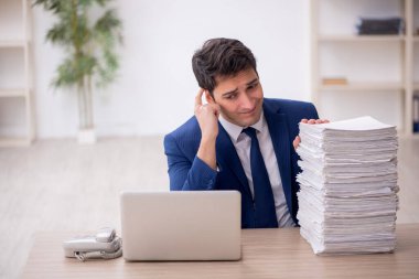 Young employee and too much work at workplace