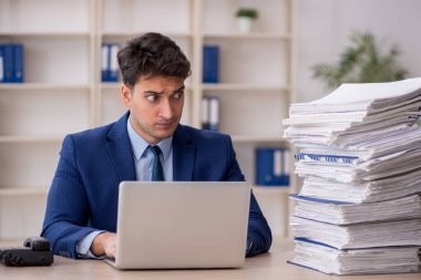 Young employee and too much work at workplace