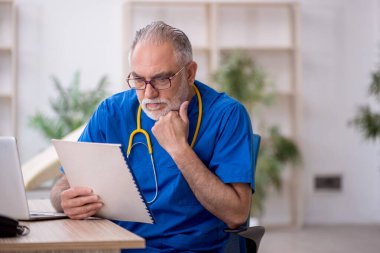 Klinikte çalışan yaşlı bir doktor.