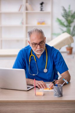 Klinikte çalışan yaşlı bir doktor.