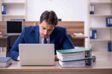 Genç işadamı ve işyerinde çok fazla iş var.