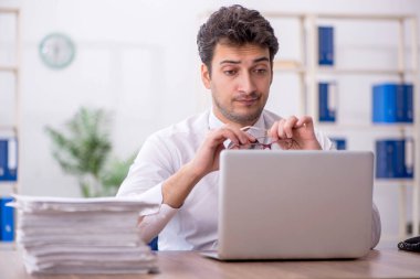 Young employee and too much work at workplace