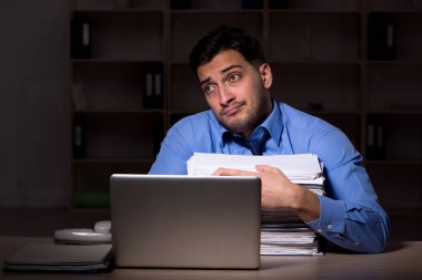 Young employee working late at workplace