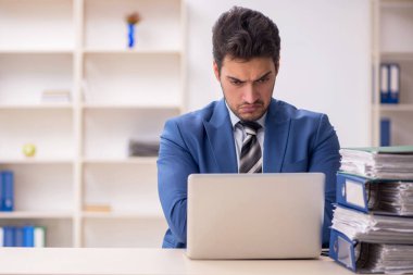 Genç işadamı ve işyerinde çok fazla iş var.