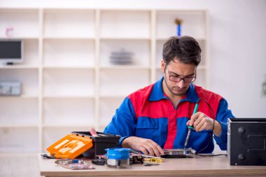 Atölyede bilgisayar tamir eden genç bir tamirci.