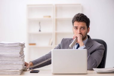 Young employee and too much work at workplace