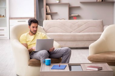 Genç erkek öğrenci salgın sırasında evden çalışıyor.