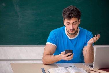 Sınıfta akıllı telefon tutan genç bir öğrenci.