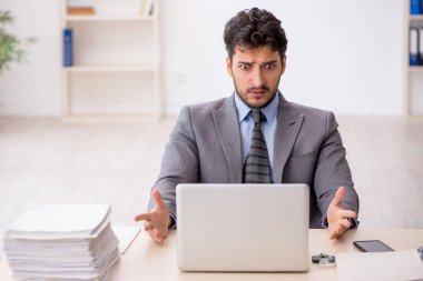 Genç bir çalışan ve ofiste çok fazla iş var.