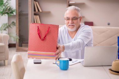 Old man with many bags in Christmas concept indoors