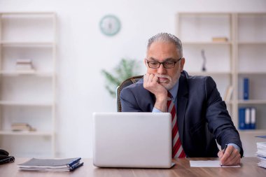 Old employee sitting at workplace