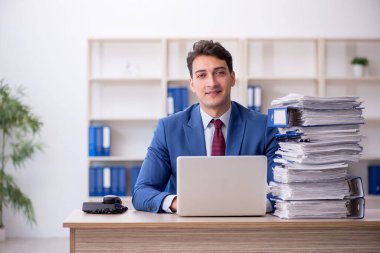 Young employee and too much work at workplace