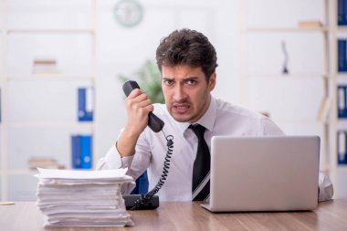 Young employee and too much work at workplace