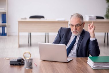 Old employee sitting at workplace