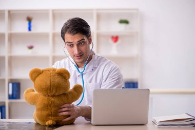 Genç doktor oyuncak ayı tutuyor.