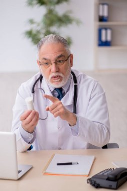 Old doctor suggesting pills at the hospital