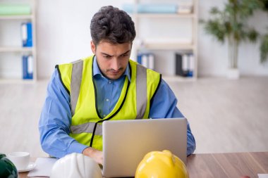 Genç mimar işyerinde oturuyor.