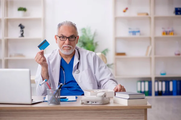 Old doctor holding credit card