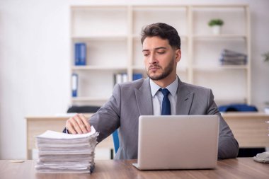 Young employee and too much work at workplace