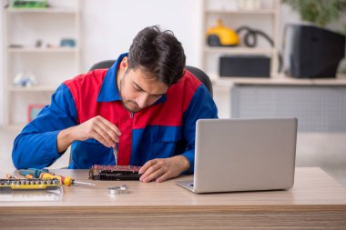 Laboratuvarda bilgisayar tamir eden genç bir tamirci.