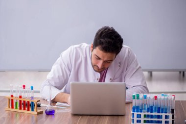 Young chemistry teacher sitting in the classroom