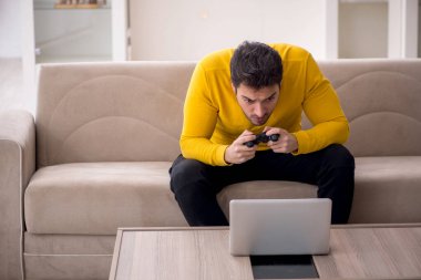 Evde video oyunu oynayan genç bir erkek öğrenci