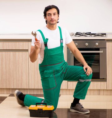 The young contractor repairing oven in kitchen clipart