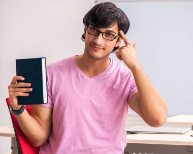 Sınıfta oturan genç erkek öğrenci.