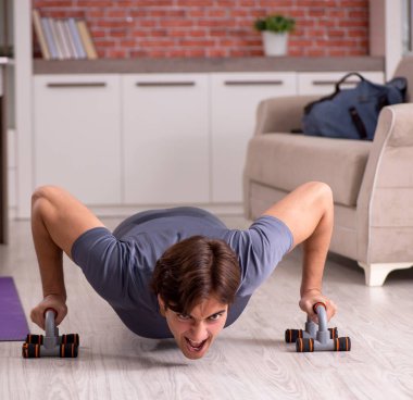 Genç yakışıklı adam evde spor egzersizleri yapıyor.