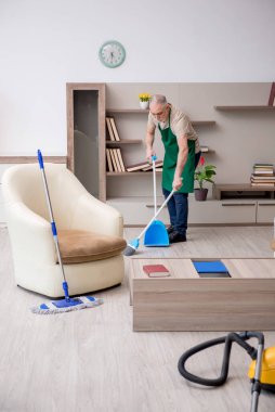 Yaşlı müteahhit evi temizliyor.