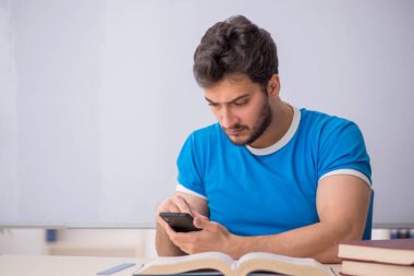 Sınıfta akıllı telefon tutan genç bir öğrenci.