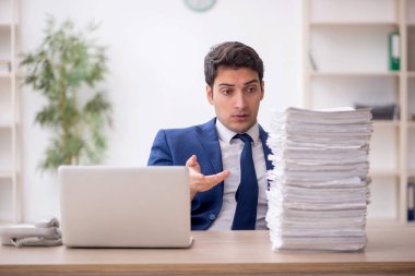 Young employee and too much work at workplace