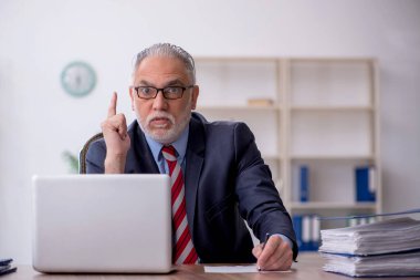 Old employee sitting at workplace
