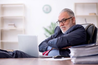 Old employee sitting at workplace