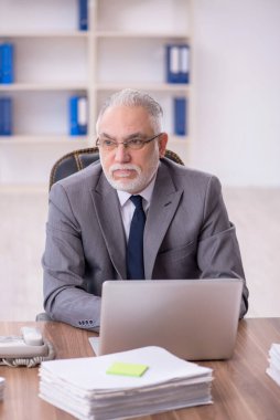 Old businessman employee unhappy with excessive work at workplace