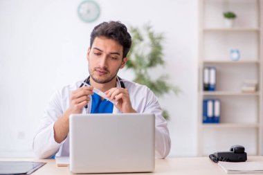 Genç doktor hastanede şırınga tutuyor.