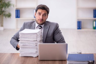 Genç bir çalışan ve ofiste çok fazla iş var.