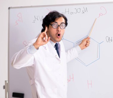 Beyaz panonun önündeki komik genç kimyager.