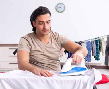 Tekerlekli sandalyedeki genç adam evde ütü yapıyor.