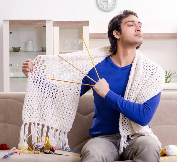 The young good looking man knitting at home