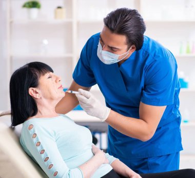 Yaşlı kadın estetik ameliyat için erkek doktoru ziyaret ediyor.