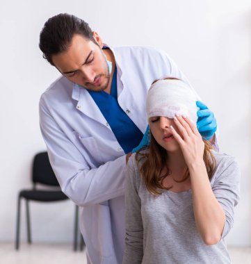 Genç yaralı kadın genç erkek doktoru ziyaret ediyor.