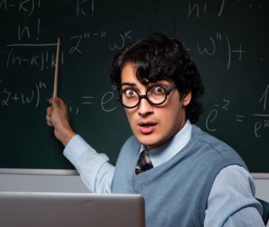 Tahtanın önündeki genç matematik öğretmeni.