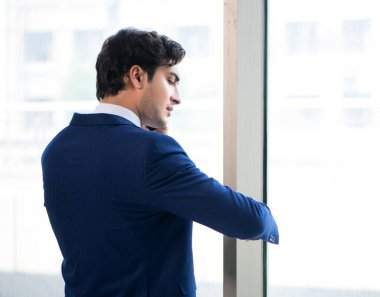 Pencerenin önünde duran genç yakışıklı iş adamı.