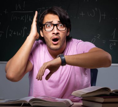 Sınıfta oturan genç erkek öğrenci.