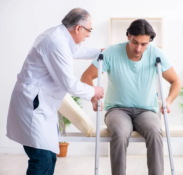 Young Leg Injured Male Patient Visiting Old Doctor — Stock Photo, Image