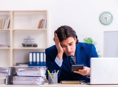 Genç işadamı ofiste oturuyor ve çalışıyor.