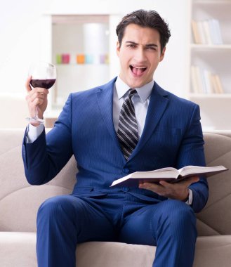 İş adamı evde oturmuş şarap içiyor.