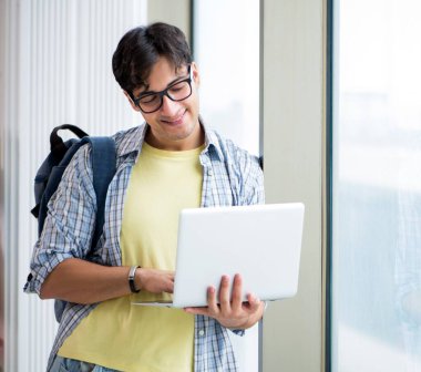 Pencerenin önünde duran genç ve yakışıklı öğrenci.